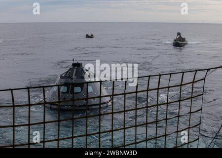 I sommozzatori della Marina degli Stati Uniti e altro personale in una barca gonfiabile a scafo rigido stanno maneggiando linee di attacco collegate a una versione di prova del modulo equipaggio Orion durante il test di recupero 5 in corso nell'Oceano Pacifico al largo della costa della California. I subacquei della Marina degli Stati Uniti in una piccola imbarcazione chiamata Zodiac sono più lontani. Il Ground Systems Development and Operations Program della NASA e la US Navy stanno conducendo una serie di test utilizzando il ponte della USS San Diego, diverse imbarcazioni e personale per prepararsi al recupero di Orion al suo ritorno dalle missioni nello spazio profondo. Il test consentirà al team di farlo Foto Stock