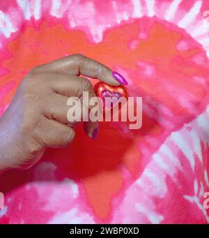 Una vista ravvicinata di una donna afroamericana con caramelle avvolte in lamina di cioccolato a cuore rosso Foto Stock