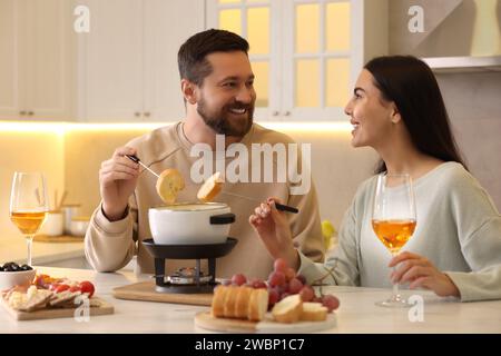 Coppia affettuosa che si gode la fonduta durante un appuntamento romantico in cucina Foto Stock