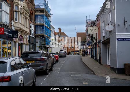 Strada con auto parcheggiate che conduce al mercato della piazza della città di Saffron Walden con alcune decorazioni natalizie Foto Stock