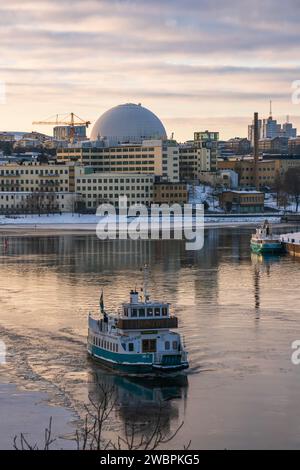 Ghiaccio sul mare a Henriksdal e Hammarby Sjöstad vicino a Stoccolma, Svezia, traghetto per pendolari linea 1 da Luma a Djurgården rompendo il ghiaccio. Cielo arancione. Foto Stock