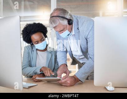 COVID, crm e dipendenti con tablet, maschera e uomo anziano che aiutano la donna di colore all'help desk del call center. Conformità, consulenza e opinione, dati crm Foto Stock