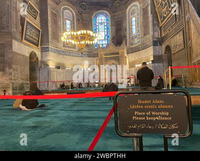 Istanbul, Turchia. 10 gennaio 2024. Un uomo prega davanti a una barriera in un'area riservata agli uomini. Le indicazioni indicano la zona tranquilla. (Al dpa 'Chiesa, museo, moschea - nuove regole per i visitatori di Hagia Sophia') credito: Linda Say/dpa/Alamy Live News Foto Stock