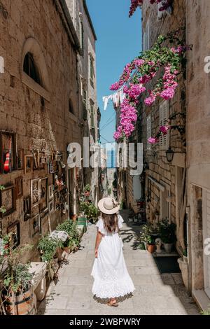 Una giovane donna che passeggia lungo un vicolo storico e pittoresco in una giornata di sole Foto Stock