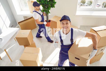 Dipendente felice di aver spostato il servizio in una nuova casa con una scatola di cartone. Foto Stock