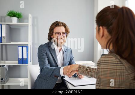 Uomini d'affari sorridenti, uomini e donne che stringono la mano saluta durante una riunione d'ufficio. Foto Stock