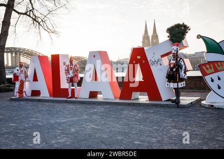 Il triumvirato della società carnevalesca Altgemeinde Rodenkirchen si trova di fronte al lettering Alaaf alto due metri nel quartiere Deutz, nel b Foto Stock