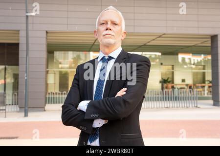 Ritratto uomo d'affari di mezza età in piedi intorno all'ufficio con le braccia incrociate. Foto Stock