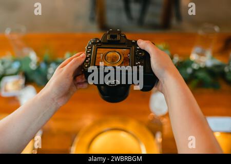 Primo piano delle mani del fotografo tenendo la fotocamera per scattare foto al tavolo Foto Stock
