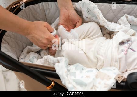 Una madre mette i calzini sul suo neonato. Foto Stock