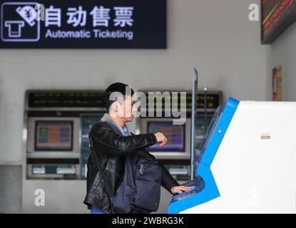 Pechino, provincia cinese di Guizhou. 12 gennaio 2024. Un passeggero prende il suo biglietto attraverso una biglietteria automatica presso la stazione ferroviaria di Congjiang, nella provincia di Guizhou della Cina sud-occidentale, 12 gennaio 2024. PER ANDARE CON XINHUA TITOLI DI JAN. 12, 2024 crediti: Luo Jinglai/Xinhua/Alamy Live News Foto Stock