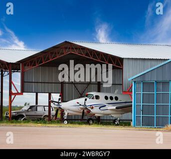 aereo a elica parcheggiato nell'hangar, auto 4x4 sullo sfondo, Foto Stock