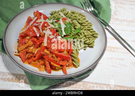Pasto vegano sano da tagliatelle verdi a base di legumi con ragù vegetale rosso da peperone e pomodoro, alto in proteine, vitamine, fibre alimentari un Foto Stock
