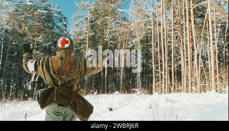 Il reenattore 4K vestito da American Soldier Medic of USA Infantry of World War II esce da Ambush con le mani in alto e si arrende alla prigionia in inverno Foto Stock