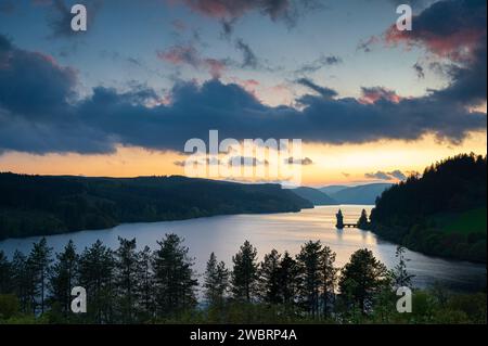 Lago Vyrnwy, situato nel Galles centrale, un'area di straordinaria bellezza naturale, al tramonto. Il cielo arancione si riflette nelle acque calme del lago Foto Stock