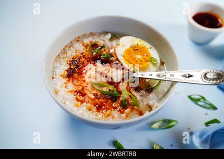 Congee in stile cinese asiatico fatto in casa con scalogni fritti con uova sode e cipolle primaverili Foto Stock