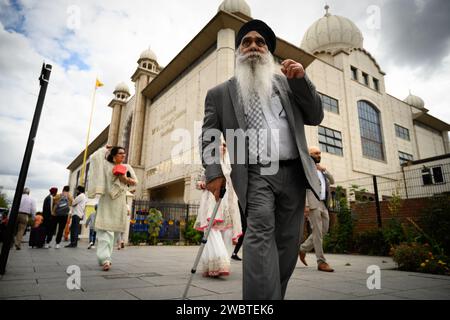 29 agosto 2022: Southall, nel quartiere di Ealing nella zona ovest di Londra, ospita la più grande comunità punjabi al di fuori del subcontinente indiano. È diventato un centro della cultura asiatica nel Regno Unito, spesso indicato come Little India. La fotografia mostra i fedeli sikh che passano davanti al tempio Gurdwara Sri Guru Singh Sabha. Foto Stock
