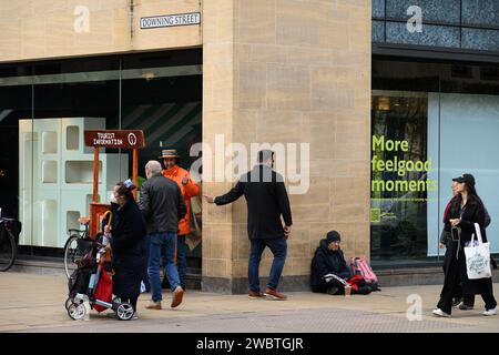 Sebbene conosciuta per la sua prestigiosa università, Cambridge è anche una delle città più disuguali del Regno Unito. C’è un’allarmante disparità tra “città e abito” in termini di ricchezza. La fotografia mostra un senzatetto che implora con un cartello che lo indica "More Feel Good Moments". Foto Stock