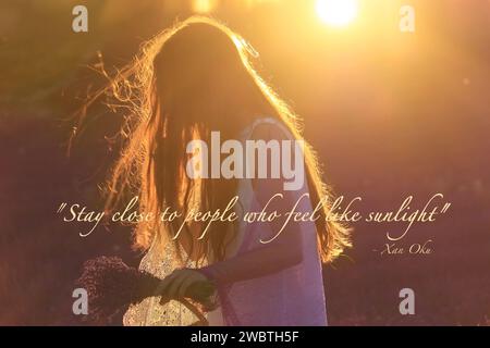 Una ragazza con un cesto in un campo di lavanda, che raccoglie fiori al tramonto. Foto Stock