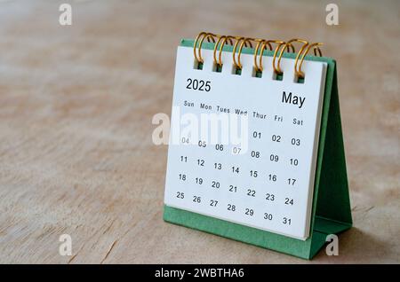 Maggio 2025: Calendario da tavolo su scrivania in legno con spazio personalizzabile per il testo. Informazioni su spazio di copia e calendario. Foto Stock
