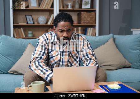 Un giovane imprenditore freelance afroamericano studia online guardando il podcast del webinar sull'ascolto dei laptop, corso di formazione, conferenza, CA Foto Stock
