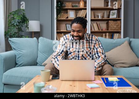 Un giovane imprenditore freelance afroamericano studia online guardando il podcast del webinar sull'ascolto dei laptop, corso di formazione, conferenza, CA Foto Stock