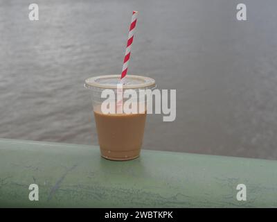 Portare via il latte in Una tazza di vetro in plastica con cannuccia Foto Stock