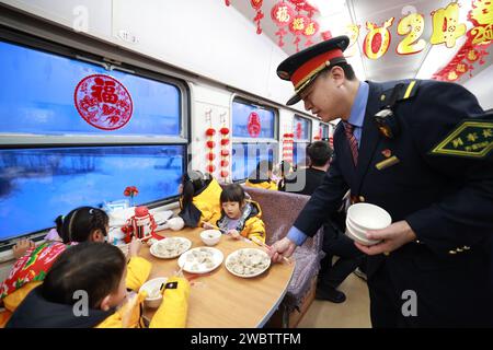 (240112) -- HARBIN, 12 gennaio 2024 (Xinhua) -- il direttore capo Zhang Yong fornisce gnocchi per i bambini della regione autonoma del Guangxi Zhuang del sud della Cina sul treno K7042, un treno che parte da Mohe diretto a Harbin nella provincia di Heilongjiang del nord-est della Cina, 5 gennaio 2024. Questi simpatici bambini sono soprannominati "piccoli mandarini di zucchero" (una specialità del Guangxi) dai netizen in Cina. Undici bambini della scuola materna di Nanning, la capitale della regione autonoma del Guangxi Zhuang, nella Cina meridionale, hanno catturato i cuori dei netizen cinesi mentre si imbarcano in un "coraggioso" viaggio nel Chin nord-est Foto Stock