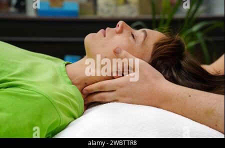 mani del terapista che esegue reiki sulla testa della donna Foto Stock