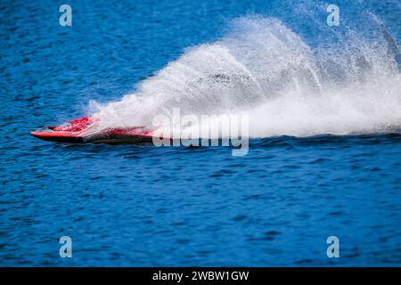 Il motoscafo RC sul rettilineo salta sull'acqua lasciandosi dietro enormi spruzzi e ondulazioni. Foto Stock