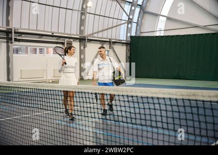 Uomo e donna che lasciano il campo dopo aver giocato a tennis Foto Stock