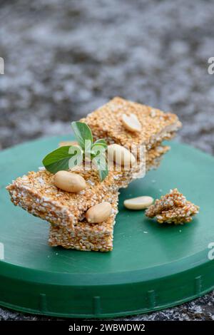 chiudi il mazzo di sesamo con sudore di zucchero scuro e semi di noci di pisello, menta verde sulla scatola di plastica verde, sfondo marrone grigio naturale. Foto Stock