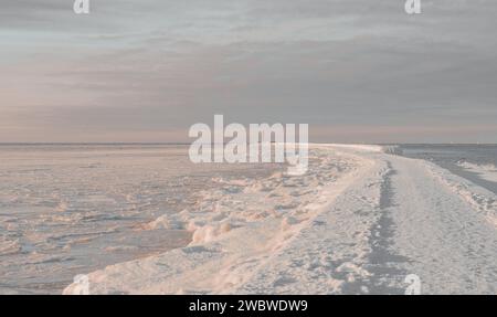 paesaggio invernale con mare ghiacciato ghiacciato cielo chiassoso e faro rosso mangalsala riga 09.01.2024 Foto Stock