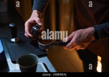 Macchina per il caffè con mani che tengono il portafiltro e la manomissione del caffè non riconoscibili Foto Stock