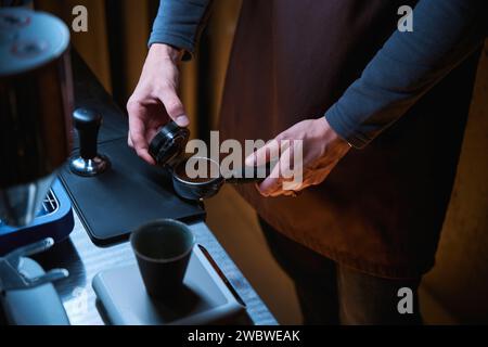 Barista mani portafilter e caffè rendendo manomissione di un caffè espresso. Foto Stock