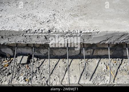 Lastra di calcestruzzo con aste metalliche di rinforzo sporgenti. Raccordi in metallo per travaso di calcestruzzo. La tecnologia dei pavimenti degli edifici. Primo piano. Focu selettiva Foto Stock