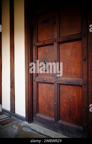 Questa porta vintage in legno presenta intricati intagli e un imponente battito in ottone Foto Stock