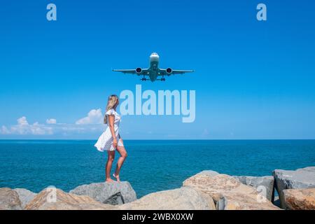 Unione mistica: Girl in White Dress on Stones, Plane Ventures the Blue Sea Foto Stock