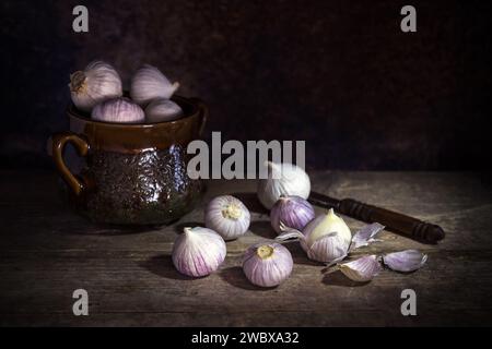 Aglio fresco con singolo guanto o aglio perlato o aglio solo, varietà di ampeloprasum Allium con una pentola per spezie su sfondo scuro Foto Stock