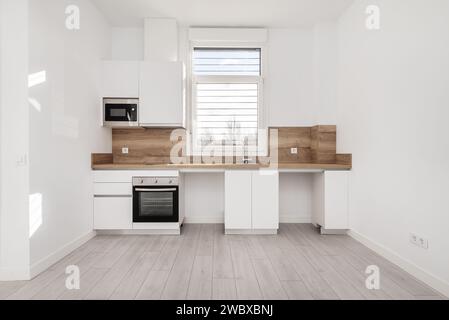 Davanti ad una cucina recentemente rinnovata con mobili in legno bianco, ripiano in legno con backsplash sulla parete dello stesso materiale e degli stessi spazi Foto Stock