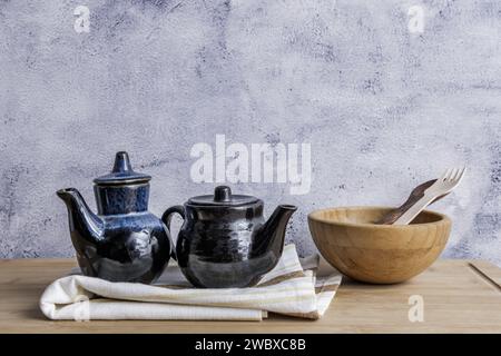 Una natura morta con utensili da cucina in legno e brocche in porcellana blu e nera su un asciugamano da cucina Foto Stock