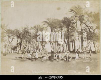 Donne e bambini riempiono caraffe d'acqua sulle rive del Nilo al Cairo, Hippolyte Arnoux, c. 1870 - c. 1891 Fotografia parte dell'album fotografico di un viaggio a Manila. Giornale del Cairo. supporto fotografico per la stampa di albumi, acquolina, spa. riva del fiume. Hoofed Animals Cairo Foto Stock
