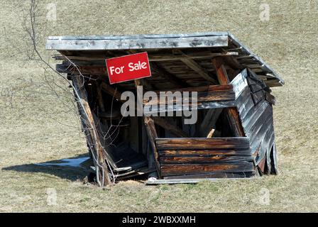 Un piccolo capannone in legno decaduto, capanna con un cartello rosso in vendita, concetto, tra Garmisch-Partenkirchen e Klais, Baviera, Germania Foto Stock