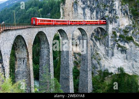 Treno rosso della Rhätische Bahn svizzera, compagnia ferroviaria Retica o Glacier Express sul viadotto Landwasserviadukt, vicino alla città di Filisur, Grigioni, Svizzerlan Foto Stock