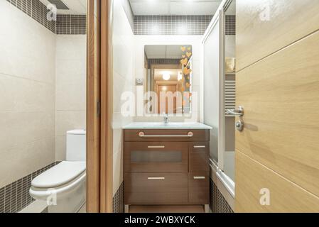 Bagno di una casa con mobili di legno scuro sotto lo specchio e WC separato Foto Stock