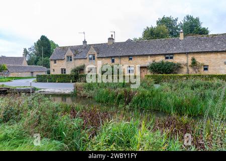 Lower Slaughter Village Cotswolds Inghilterra e filari di cottage e case in pietra color miele inglesi accanto al River Eye, Inghilterra, Regno Unito, autunno 2023 Foto Stock