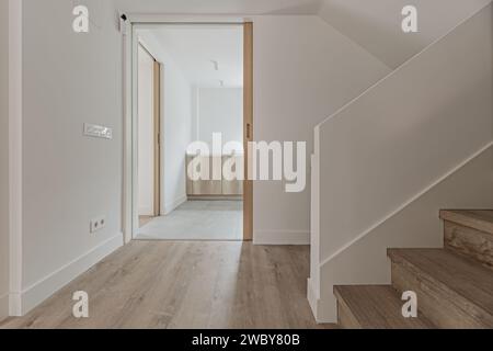 Lobby di una casa con pareti dipinte di bianco liscio, scalinate e pavimenti in legno coordinati. Foto Stock