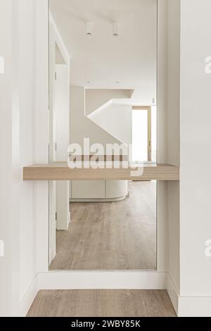 Corridoio di una casa moderna recentemente rinnovata con una mensola in legno di quercia bianca nel mezzo di un grande specchio a figura intera Foto Stock