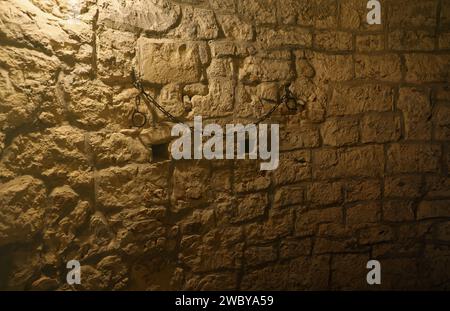 Schiavitù e schiavitù, robusti maniglioni in acciaio su pareti di pietra nella cantina o nella tomba del castello Foto Stock