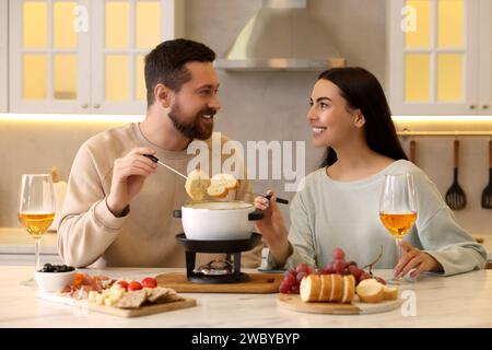 Coppia affettuosa che si gode la fonduta durante un appuntamento romantico in cucina Foto Stock